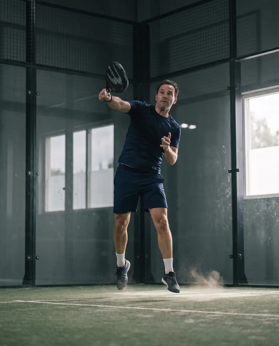 Joueur de padel en pleine volée sur un terrain couvert
